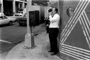 George Roussos tries out a new camera lens, 1979.
