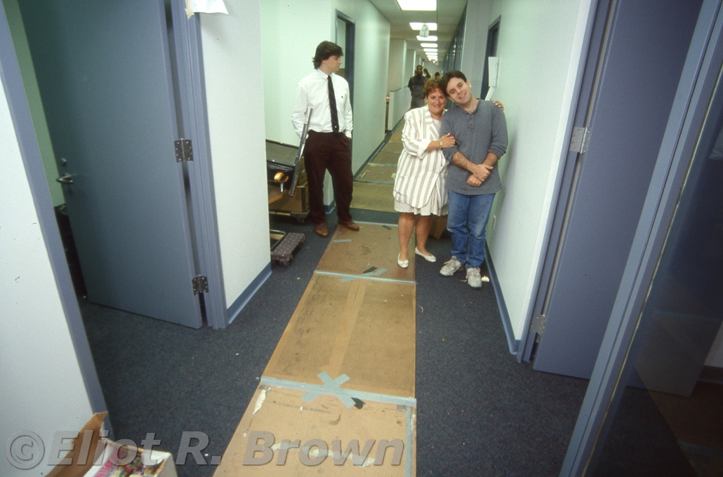 Office Manager Susan Ehrenreich comforts Dave Wohl. She’ll get him his office. Don’t know who the fellow is to the left– an 11th Floor sinecure is my best guess.