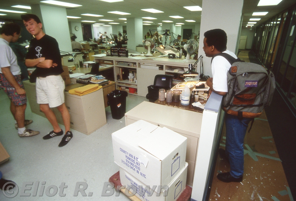 A step back from George's desk-- at the wall freelancer Keith Williams is leaning on. There's that freelancer artist Manny Galen again. To his left is unknown.