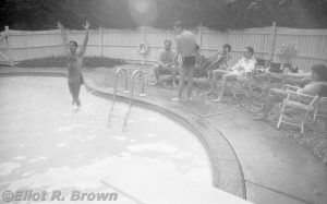 From the opposite end of the Macchio Family Pool—a kidney-shaped pool or a pool-shaped kidney—Raf is doing the Reverse Namor Leap and Jack, with his back to us, appears to be winding up for a towel-snap.