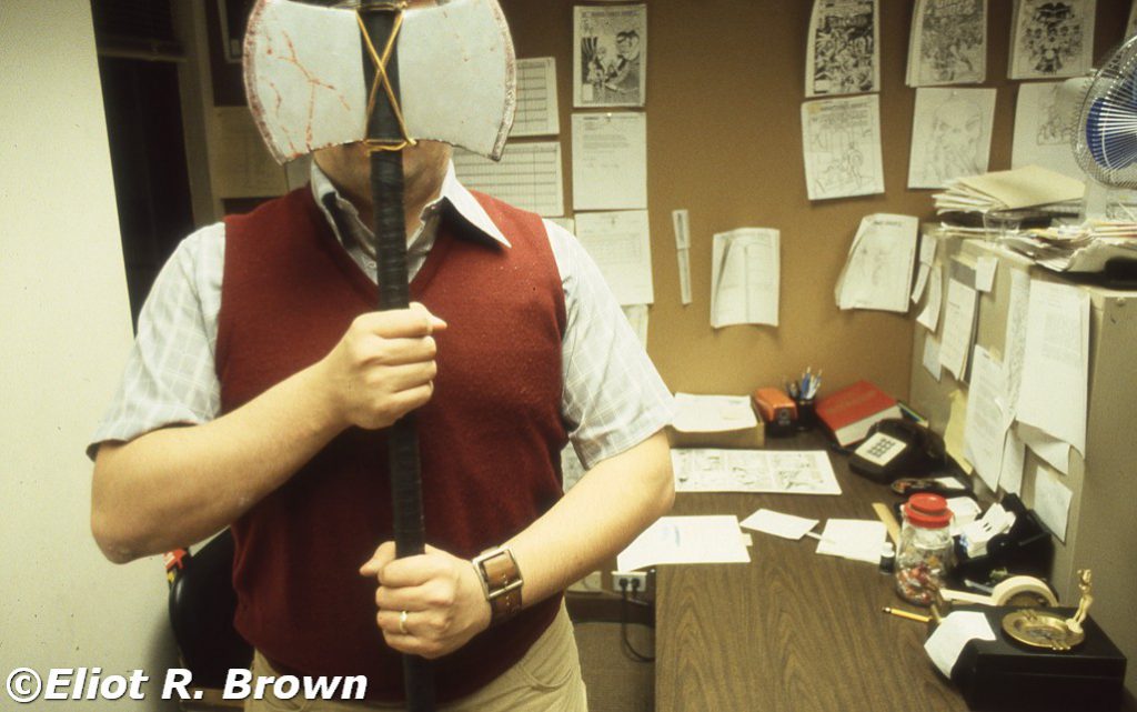 A prop axe I made for Tom. Specific reason un-remembered. But probably something to do with his briefly-used nick-name, “Hatchet Man” or Tom The Executioner, something like that! This was Tom’s office in the “new” (387 Park) offices. Of note is that Tom had set up a wall of flat files and filing cabinets in front of his deck. The windows are visible behind him. This was a barrier to riled up freelancers with their crofter’s hooks and fiery brands.