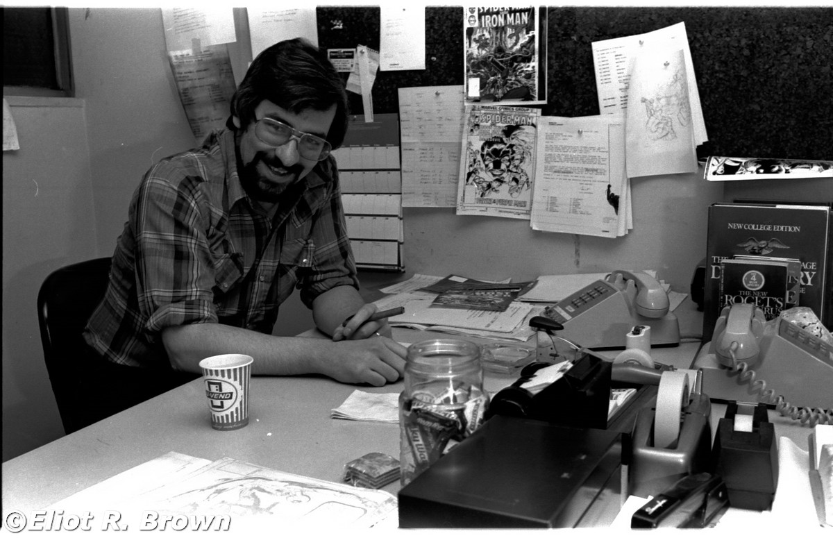 Happy Tom. So early in my photographing Tom, he had not yet adopted his persona of the snarling, camera-avoiding recluse. Note the happy little jar of small candy bars. Also note the horrid cigarillo, an indication of the office smoking policies of the day. To the right, this is what he was looking at. Not all the time, of course. Mark Gruenwald his assistant.